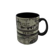Black-and-white New Orleans souvenir mug with wraparound sketches of French Quarter buildings, carriage, streetcar, and bridge