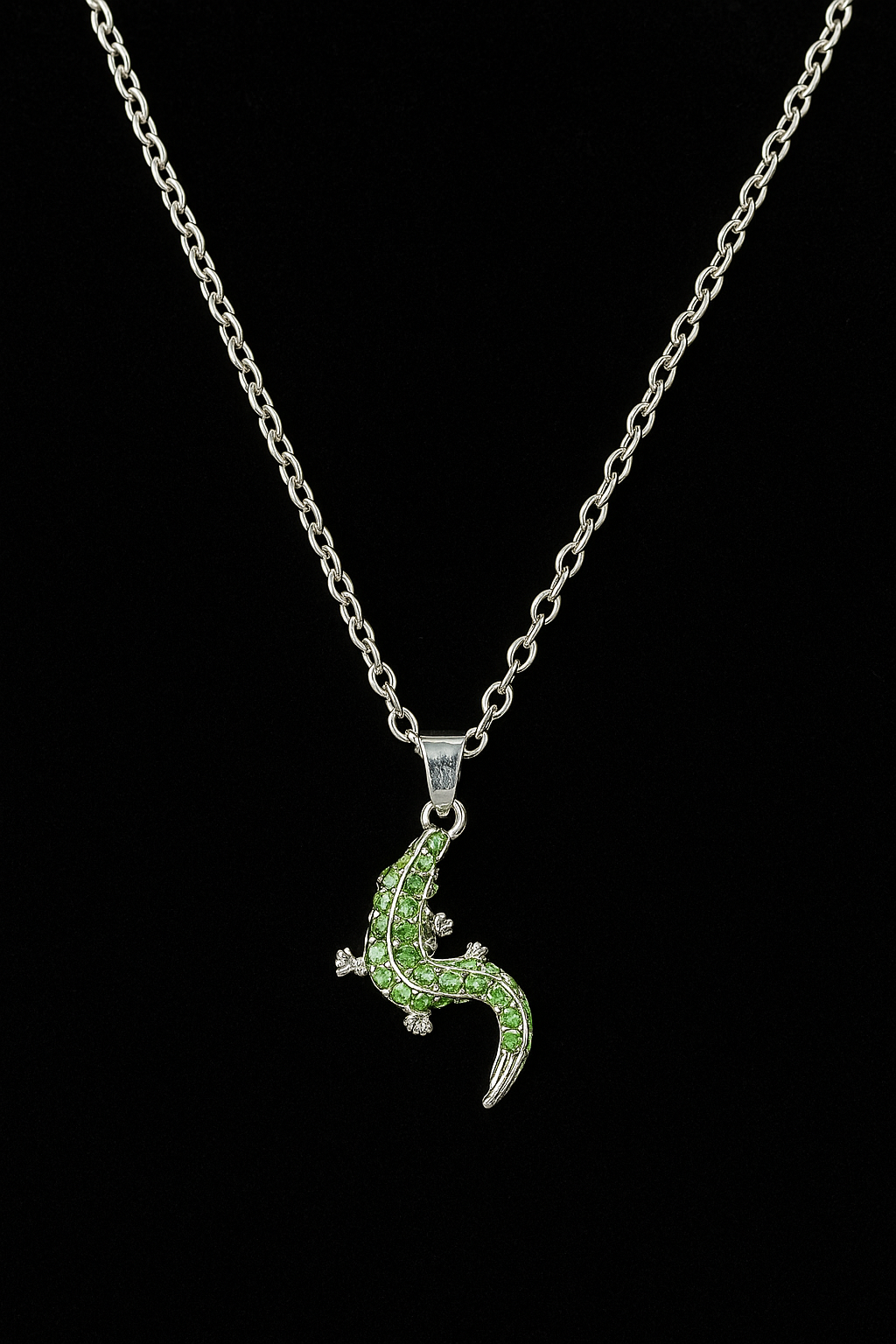 Silver necklace with a green lizard pendant on a black background