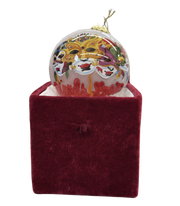 Decorative ornament with a colorful design on top of a red velvet box against a white background