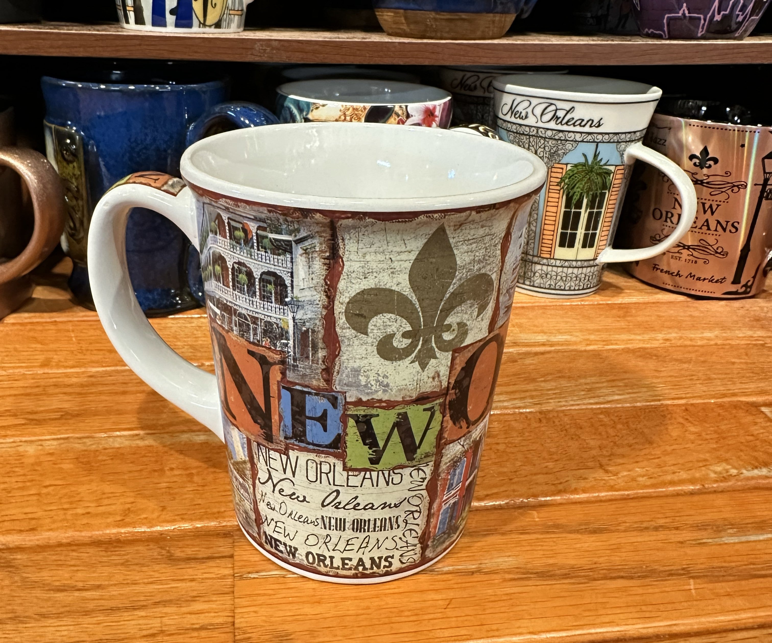 Ceramic mug with a weathered fresco-style collage featuring “New Orleans” text, St. Louis Cathedral, saxophone player, steamboat, Mardi Gras beads, and French Quarter balconies.