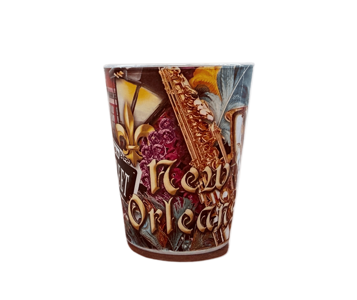 A New Orleans themed shot glass featuring a detailed collage of the city's iconic imagery, including a fleur-de-lis, a golden cathedral facade, a bayonet, and the words 'New Orleans' in stylized lettering.