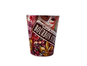 A novelty shot glass featuring a Mardi Gras themed design with masks, beads, fleur-de-lis, and a banner reading 'Rue Bourbon BOURBON STREET'.