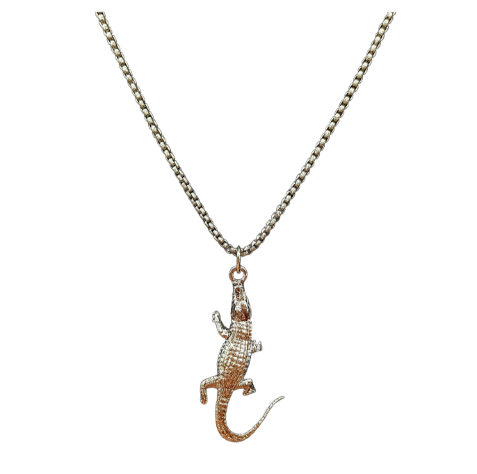 A necklace featuring a detailed alligator or crocodile pendant with a textured, pave-set finish, suspended from a silver-toned curb chain against a plain white background.