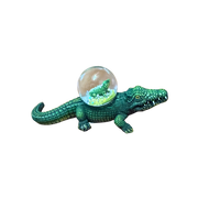 Green crocodile figurine with a transparent ball on a white background