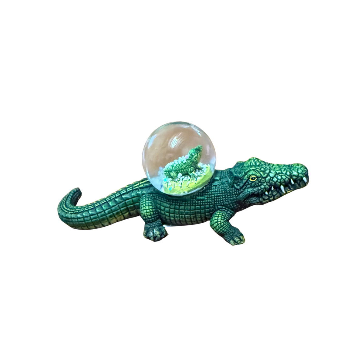 Green crocodile figurine with a transparent ball on a white background