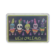 A rectangular printed card or coaster with rounded corners, shown in a clear plastic sleeve on a white background. The design features five colorful sugar skull figures above the words “NEW ORLEANS” in yellow-green lettering on a dark charcoal background.